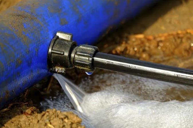 Close-up of a metal pipe with foam and dirt around it.